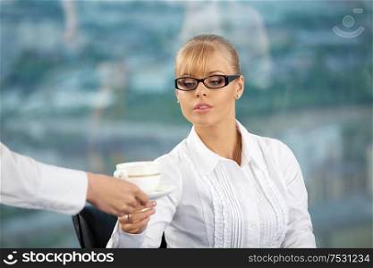 Someone brings the beautiful business lady a coffee cup at office