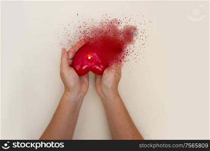 Someones hands holding red burning and scattering heart, top view. Hands holding heart