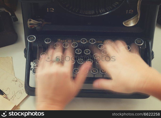 Someones hands typing on black vintage typewriter, top view, retro toned. typewriter on table