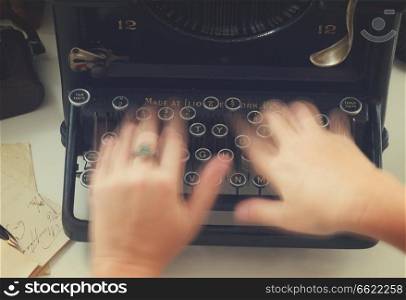 Someones hands typing on black vintage typewriter, top view, retro toned. typewriter on table