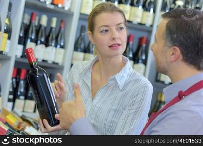 sommelier giving woman recommendation for bottle of wine