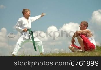 son and father practicing karate on the nature on a sunny day