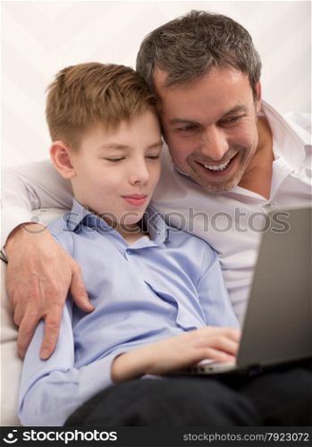 Son and father with laptop at home. They found something interesting and looking at screen. Happy dad and son with laptop at home
