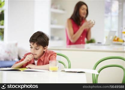 Son Does Homework As Mother uses Laptop In Background