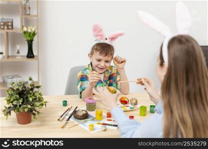 son enjoying paint eggs with his mom