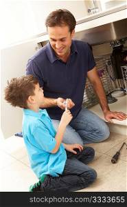 Son Helping Father To Mend Sink In Kitchen