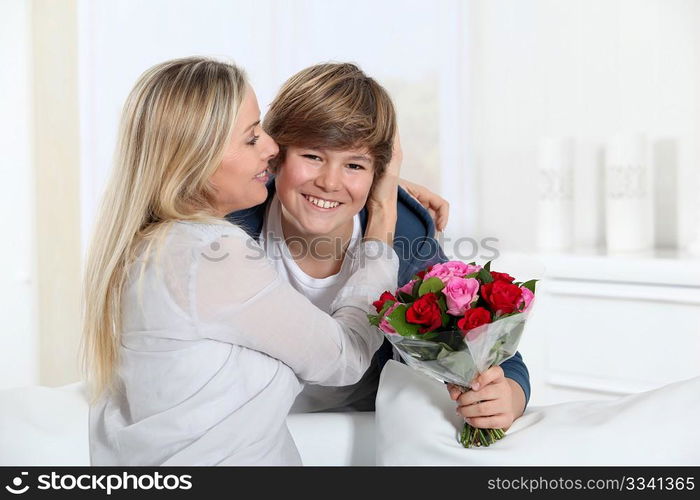 Son offering bunch flowers on mother&acute;s birthday