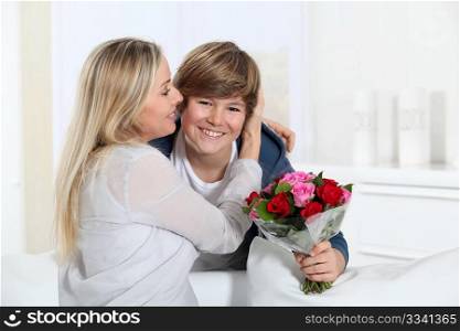 Son offering bunch flowers on mother&acute;s birthday