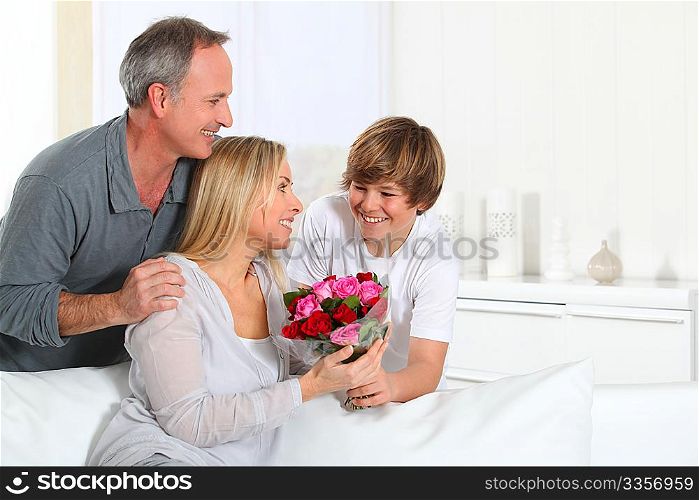 Son offering bunch flowers on mother&acute;s birthday
