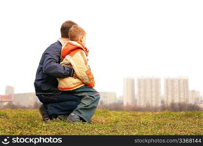 son on lap of father outdoor in city