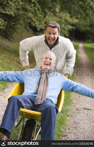 Son pushing senior father in wheelbarrow