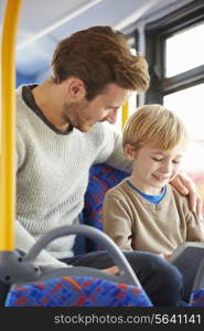 Son Using Digital Tablet On Bus Journey With Father