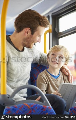 Son Using Digital Tablet On Bus Journey With Father
