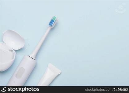Sonic toothbursh and oral hygiene products. Electric tooth brush with toothpaste and dental floss on blue background.