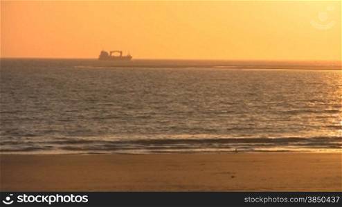 Sonnenuntergang am Sandstrand, Schiff am Horizont
