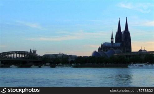 Sonnenuntergang nber K?ln, davor ein Schiff auf dem Rhein und die beleuchtete Stadt mit Mondenschein