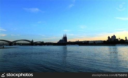 Sonnenuntergang nber K?ln, im Vordergund der Rhein und nachts die beleuchtete Stadt im Mondenschein
