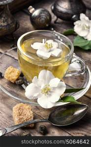 soothing tea with Jasmine flowers. glass of herbal tea with the aroma of Jasmine flower on wooden background