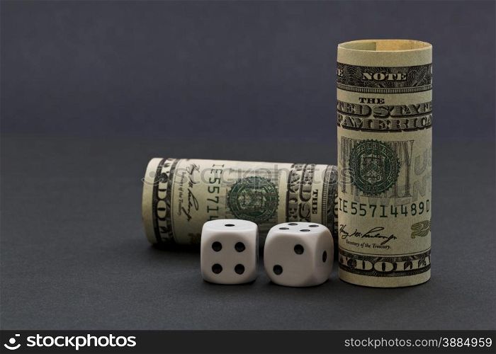 Sophisticated gray background image with United States dollars and black and white dice reflects risk in financial environment with opportunities for success.