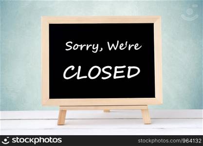 Sorry, we're close on blackboard over green wall background, business hours sign
