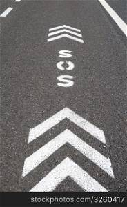 SOS sign with direction arrows on an emergency lane of a freeway. SOS emergency freeway lane