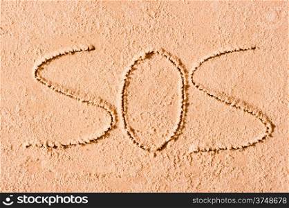 SOS written in the sand on the beach in large letters