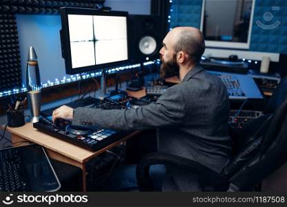 Sound engineer looking at the monitor on remote control panel in the recording studio. Musician at the mixer, professional audio mixing