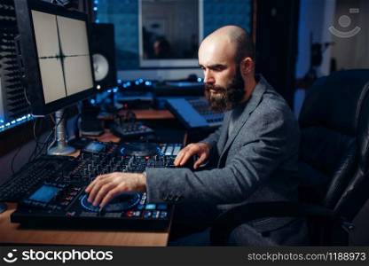 Sound engineer working at the remote control panel in the recording studio. Musician at the mixer, professional audio mixing