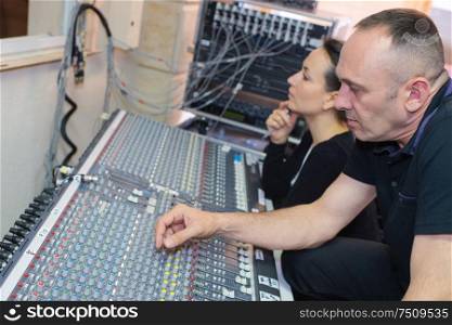 sound engineers working at mixing panel in recording studio