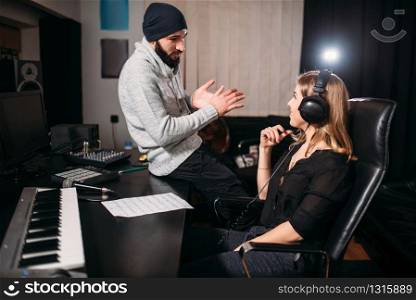 Sound producer work with female singer in headphones, song record in music studio. Professional digital sound technologies. Sound producer with female singer in music studio
