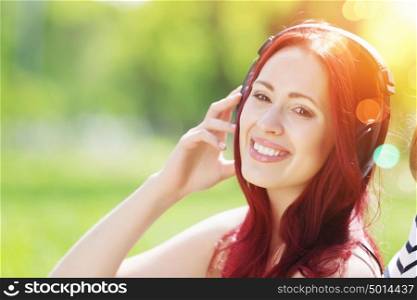 Sounds of nature. Young pretty woman enjoying music in headphones in summer park