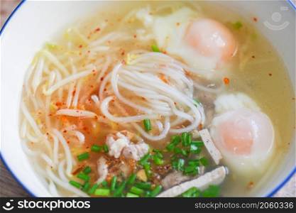 Soup bowl, soup noodle pork white noodle with vietnamese pork soft boiled eggs and bean sprout vegetable spring onion in soup bowl on wooden table, Thai Asian food