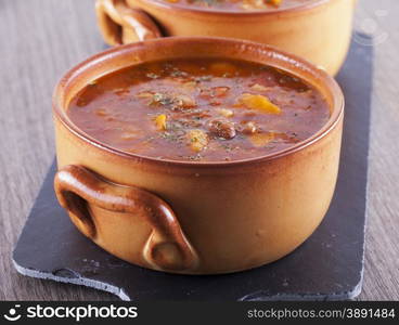 Soup in clay bowl over black stone chopping board, horizontal image