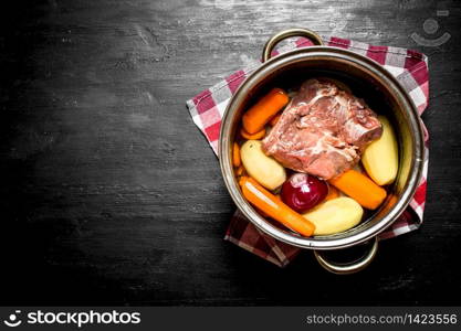 Soup with beef, carrots and fresh potatoes in the pan. On a black wooden background.. Soup with beef, carrots and fresh potatoes in the pan.