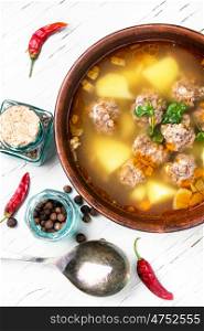 soup with meat balls. Meat soup in clay dish on a light wooden background