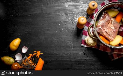 Soup with meat, vegetables and spices. On a black wooden background.. Soup with meat, vegetables and spices.