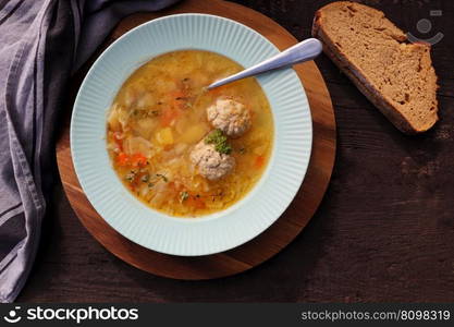 Soup with meatballs on dark background, gray linen napkin. Healthy meatball soup with vegetables. Top view .. Soup with meatballs on dark background, gray linen napkin. Healthy meatball soup with vegetables. Top view