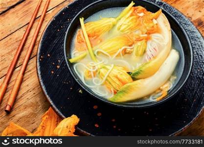 Soup with rice noodles and pumpkin flowers.Asian vegan soup.. Vegan noodle soup with zucchini flowers