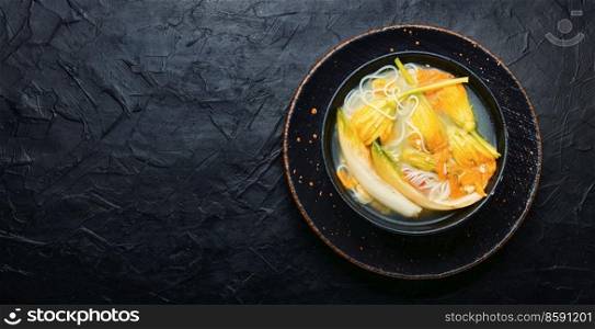 Soup with rice noodles and pumpkin flowers.Asian vegan soup.Copy space. Vegan noodle soup with zucchini flowers