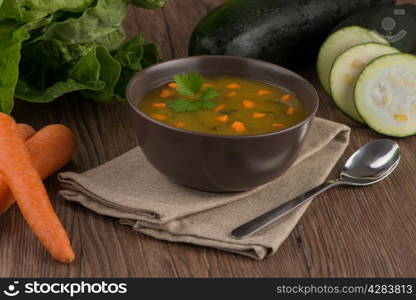 Soup with vegetables on wooden table.