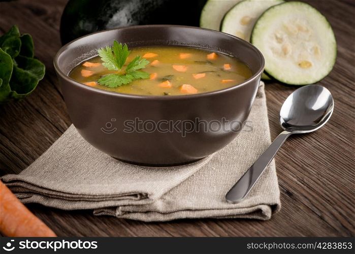 Soup with vegetables on wooden table.
