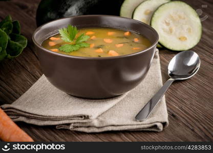 Soup with vegetables on wooden table.