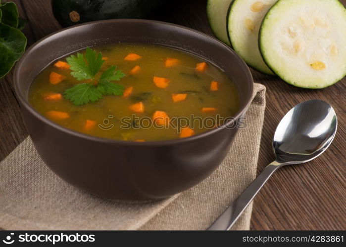 Soup with vegetables on wooden table.