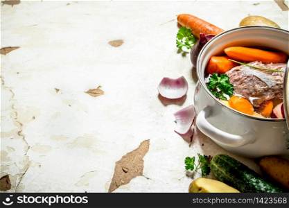 Soup with vegetables, pork, spices and herbs in a saucepan. On rustic background.. Soup with vegetables, pork, spices and herbs in a saucepan.