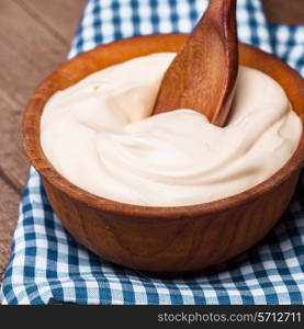 Sour cream in a wooden bowl. Farm organic product