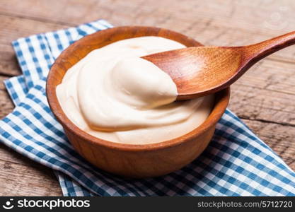 Sour cream in a wooden bowl. Farm organic product