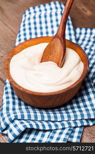 Sour cream in a wooden bowl. Farm organic product