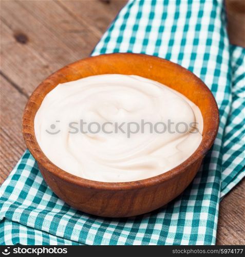 Sour cream in a wooden bowl. Farm organic product. The sour cream