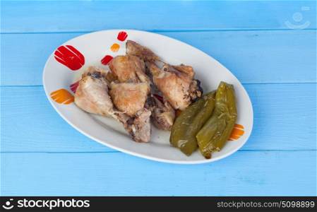 Source of chicken thighs with baked peppers on a blue wooden table