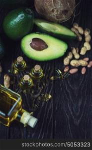 source of omega 3. Oil of avocado with fish oil pills and peanut - source of omega 3 on a dark wooden background